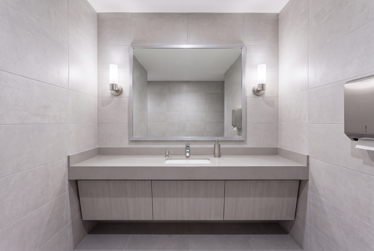 Updated commercial restroom or office wash area with a framed wall mirror